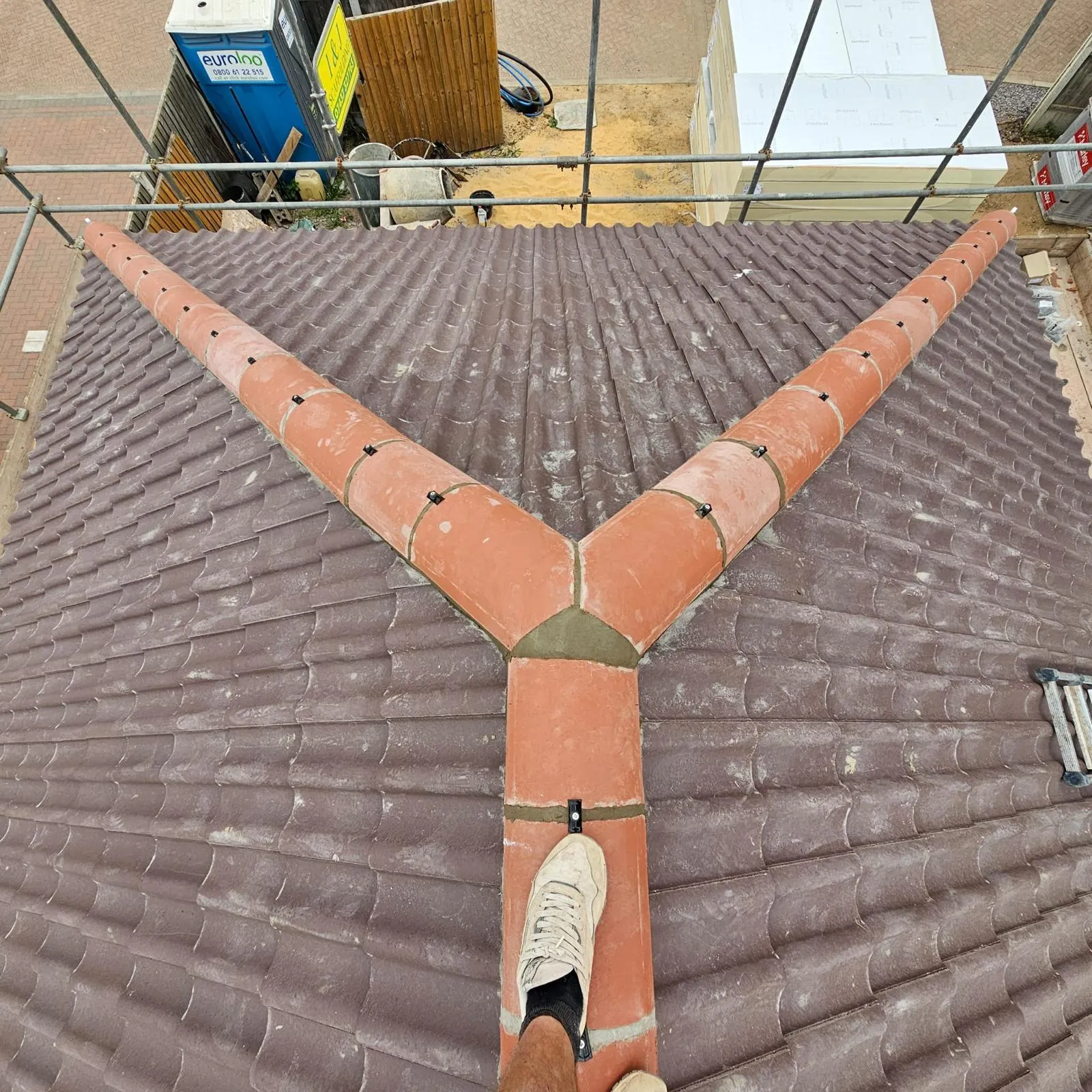 New tiled roof with terracotta hip and ridge tiles meeting at a junction