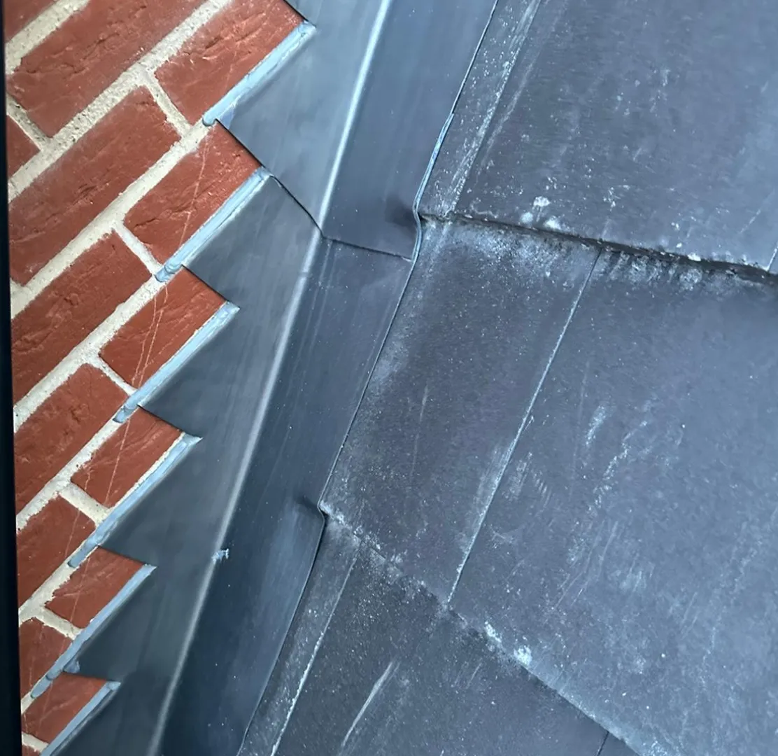 Lead step flashing dressed around a brick chimney